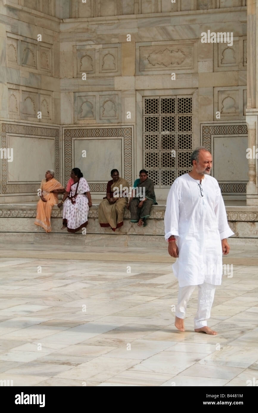 Un uomo cammina davanti a un gruppo di donne sedute sui gradini del Taj Mahal Foto Stock