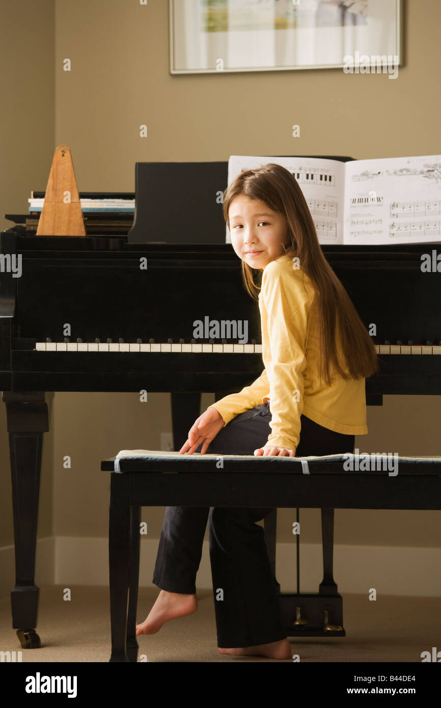 Ragazza asiatica seduta al pianoforte Foto Stock