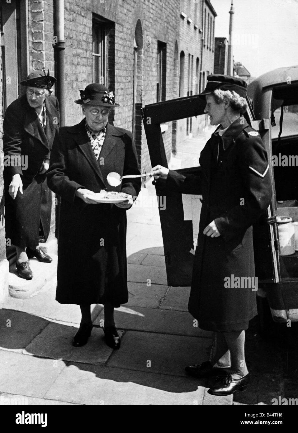 La Croce Rossa britannica Pasti su ruote Giugno 1946 La signora Emily Hart prendendo parte al suo pasto di mezzogiorno da parte della Croce Rossa helper nella cordiale Foto Stock