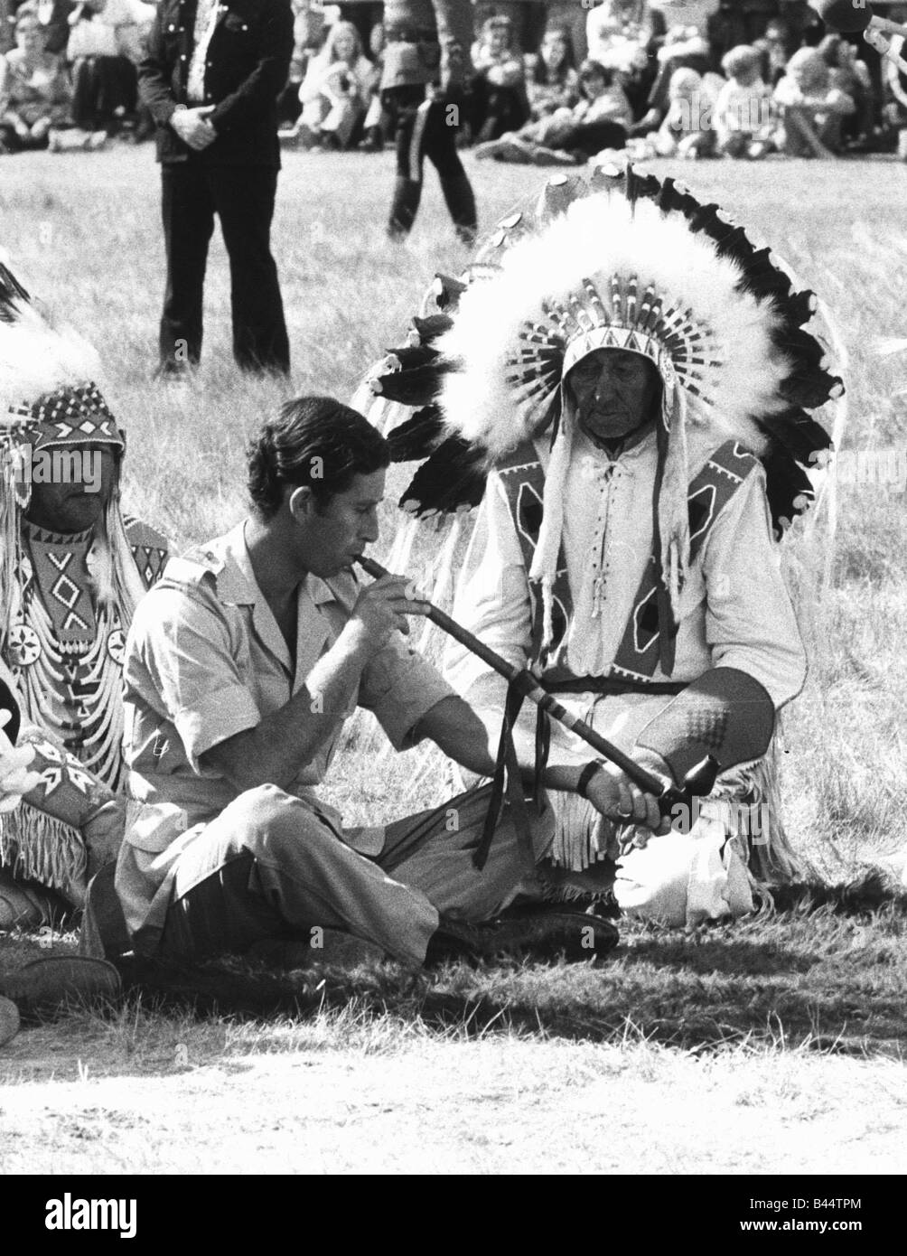 Il principe Charles frequentando un Blackfoot cerimonia indiana a Calgary in Canada Luglio 1977 sbuffando un tubo di pace guardato da uomo della medicina Foto Stock