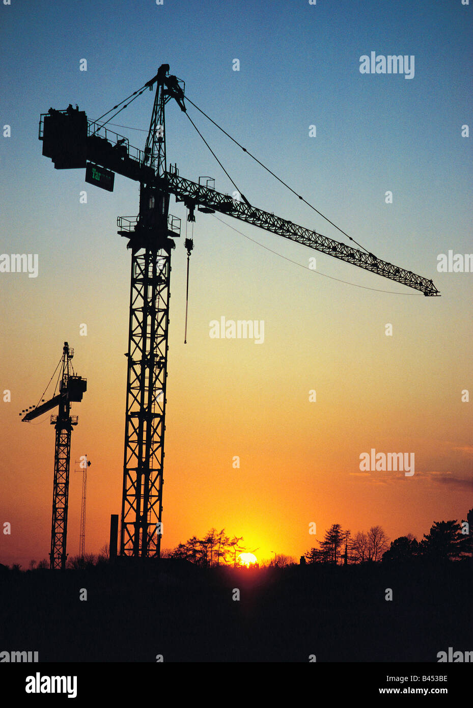 Silhouette di sito in costruzione di gru contro il tramonto Foto Stock