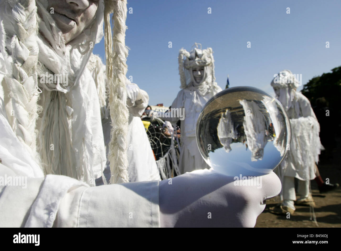 Artisti di prestazioni vestito di bianco e trattenere le sfere di cristallo si muovono attraverso la folla in uno stadio mondiale area Foto Stock