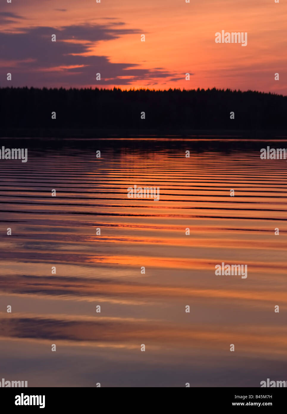 Foto di astrazione: onde sull'acqua del tranquillo lago di foresta nella notte bianca di sfondo al tramonto Foto Stock