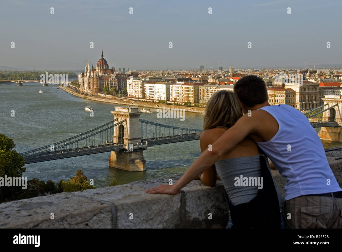 Budapest Chain Bridge oltre il Fiume Danubio con il Parlamento in background sul lato Pest con coppia romantica sul Castello di Buda si affacciano Foto Stock