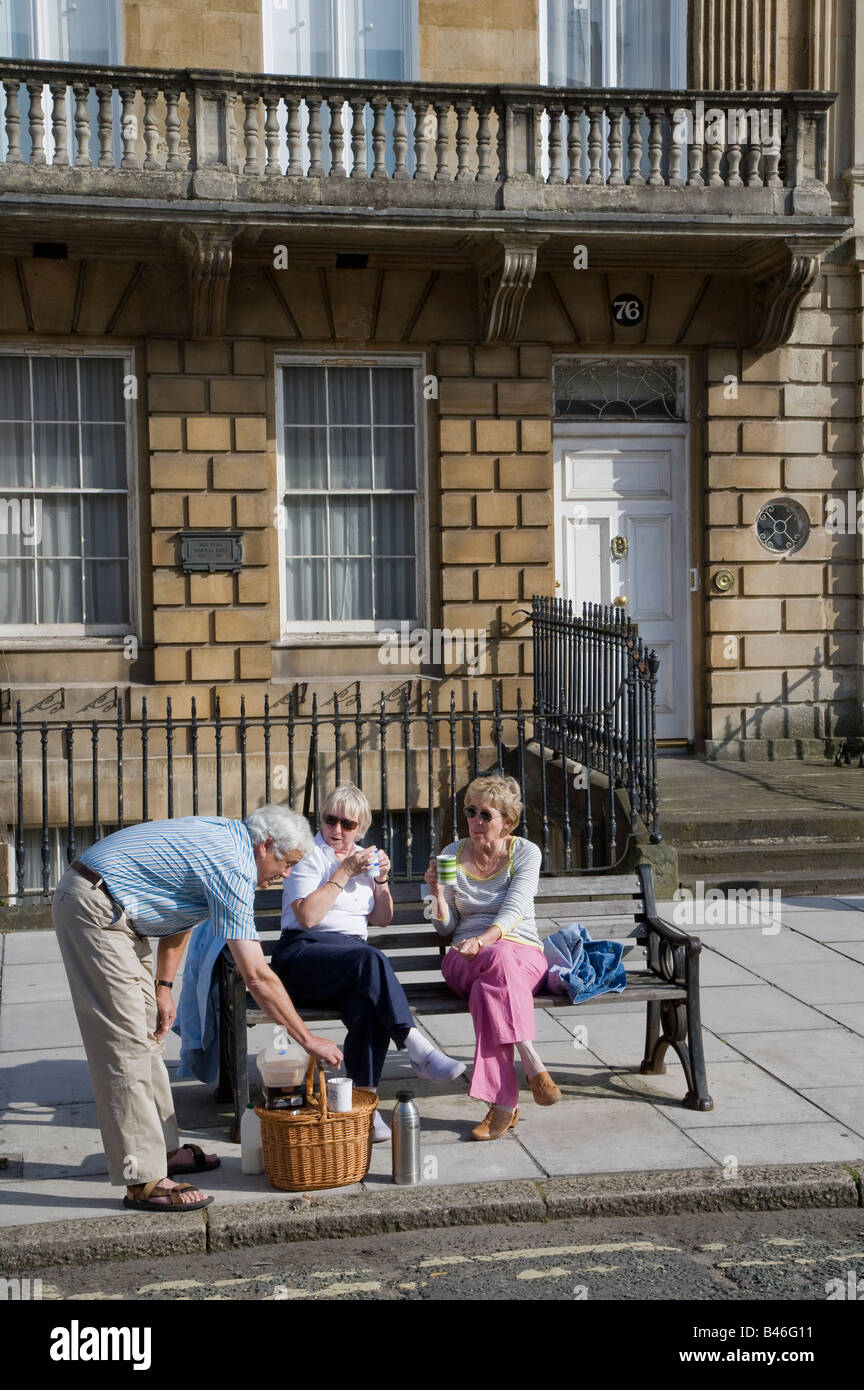 Le persone aventi un tè picnic sulla panchina in street Bath Regno Unito Foto Stock