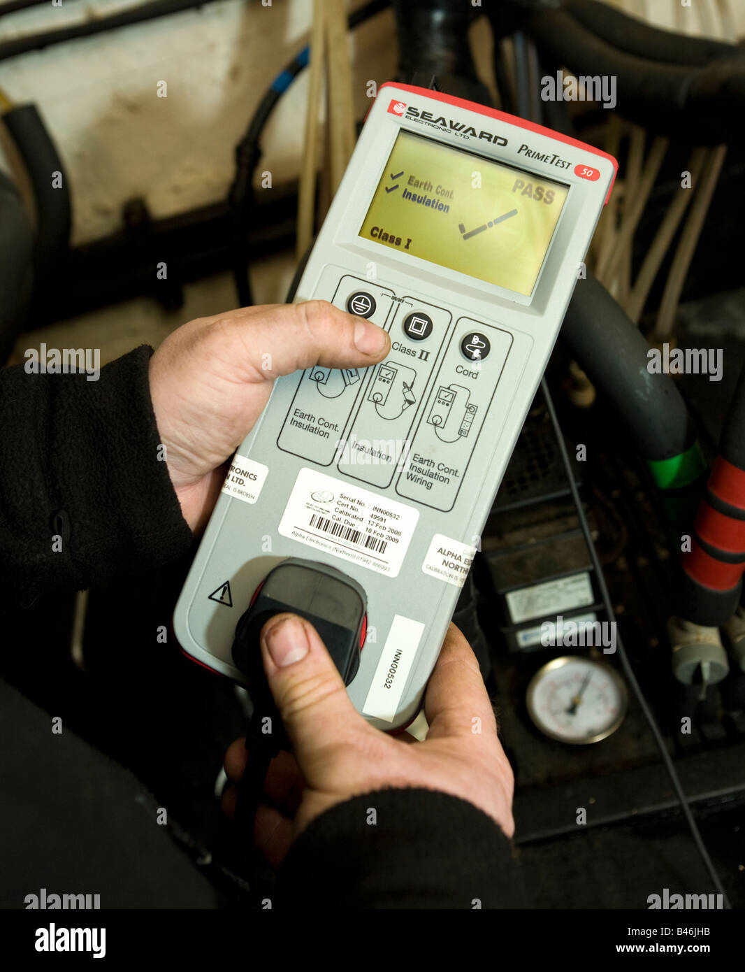 Ingegnere facendo una sicurezza elettrica PAT test con una batteria alimentata metro, il display LCD mostra un pass Foto Stock