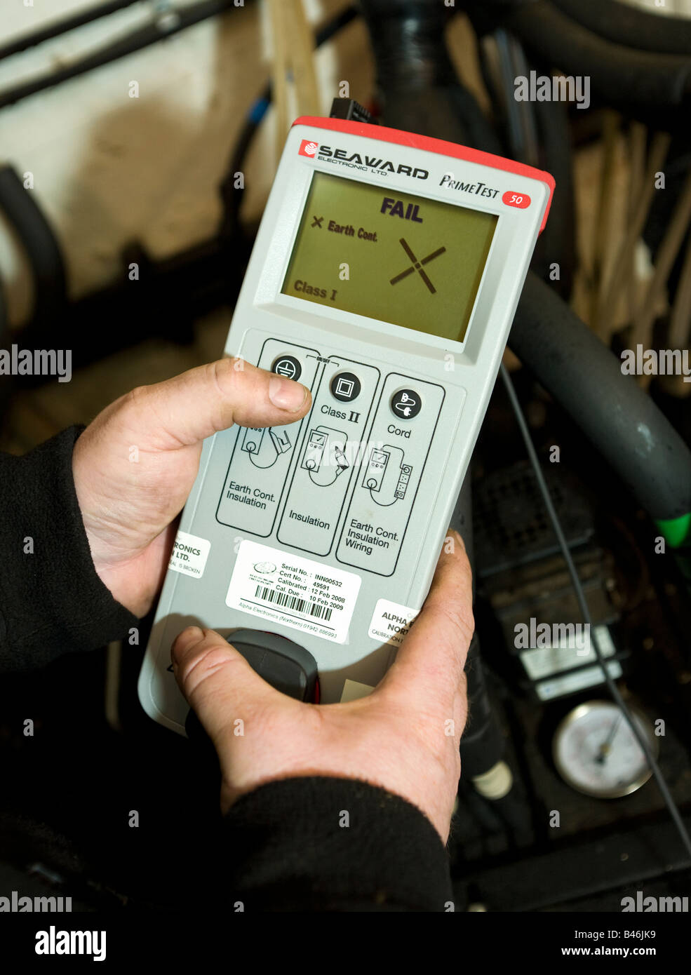 Ingegnere facendo una sicurezza elettrica PAT test con una batteria alimentata metro, il display LCD mostra un fail Foto Stock