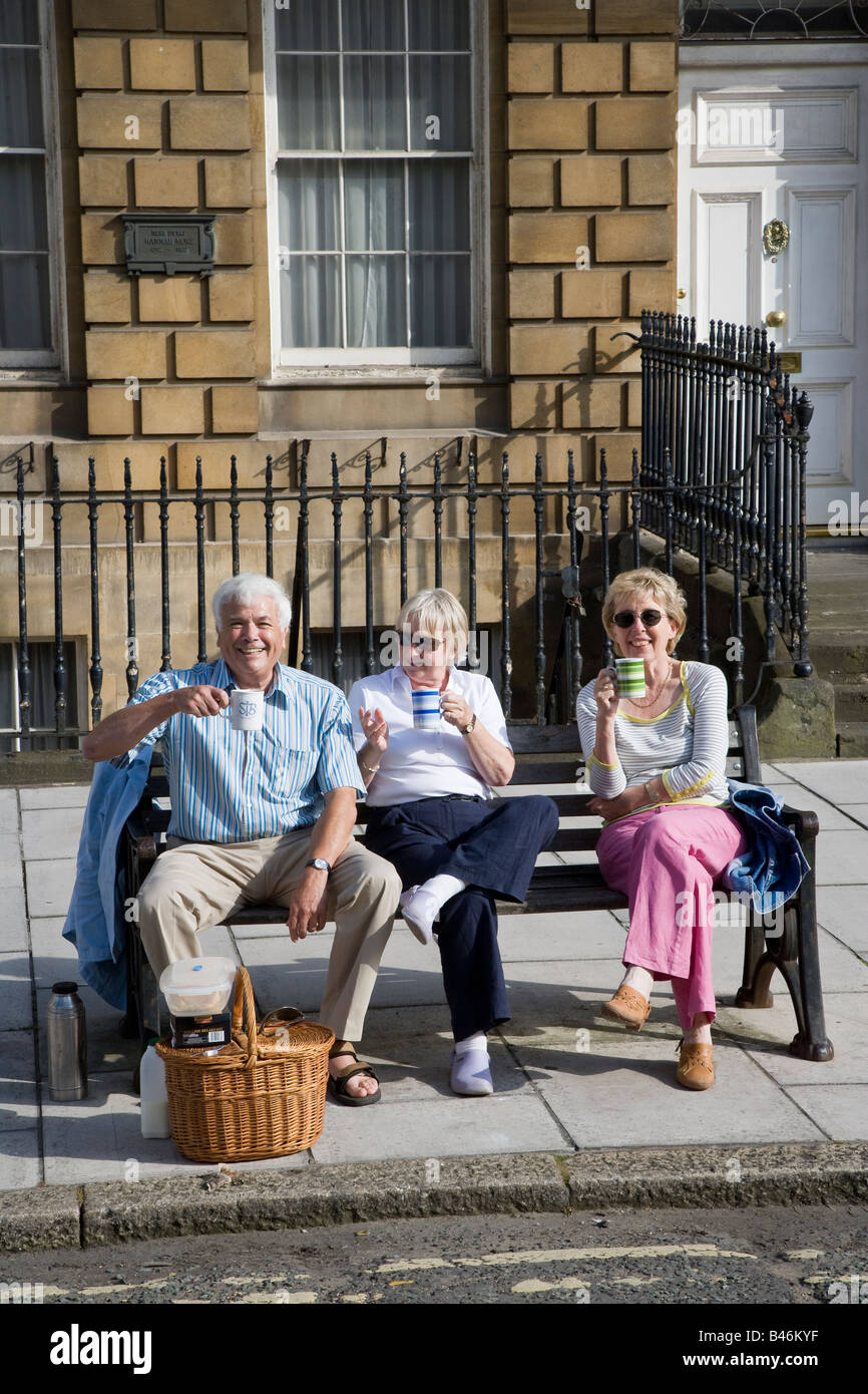 Le persone aventi un tè picnic sulla panchina in street Bath Regno Unito Foto Stock