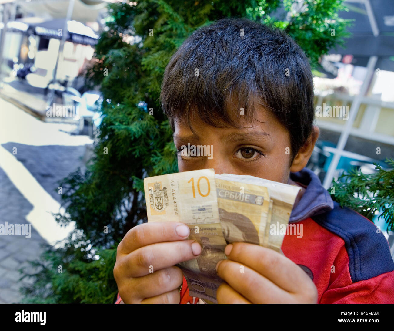 A Roma o ragazzo zingaro mendicante per le strade di Nis Serbia con alcuni dei soldi ha raccolto di elemosina Foto Stock