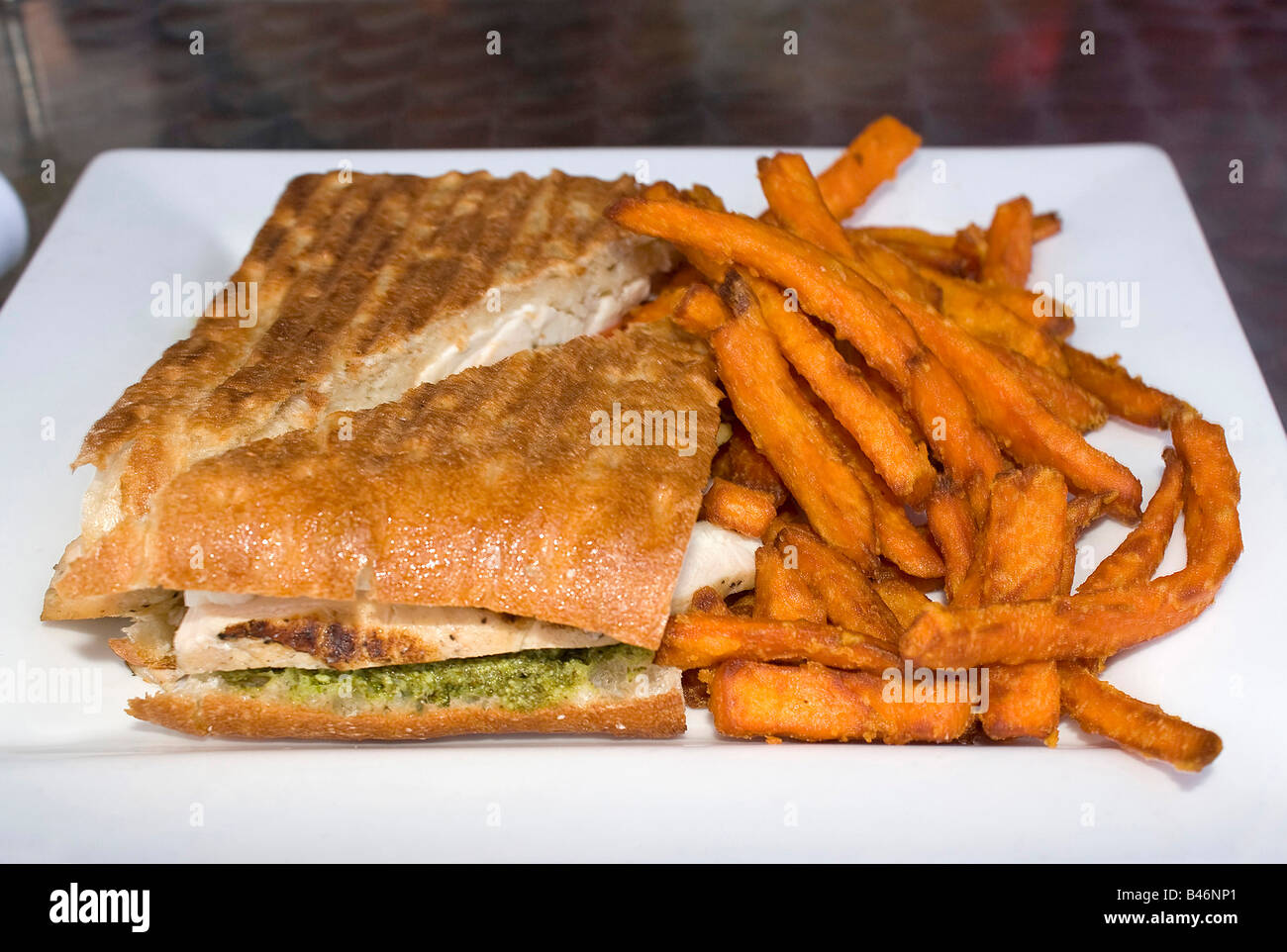 Un delizioso pollo pesto e pomodoro panini sandwich con un lato della patata dolce patate fritte Foto Stock