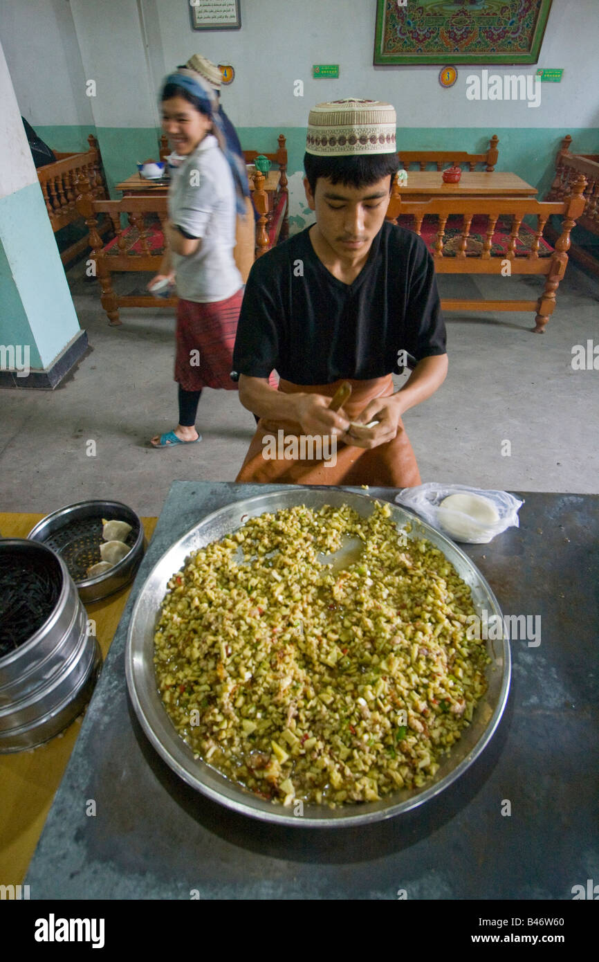 Uyghur rendendo Manti dietro un enorme piatto di riempimento di Yarkand nella provincia dello Xinjiang Cina Foto Stock