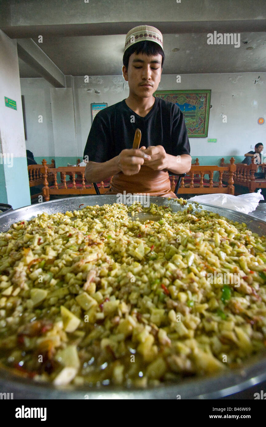 Uyghur rendendo Manti dietro un enorme piatto di riempimento di Yarkand nella provincia dello Xinjiang Cina Foto Stock