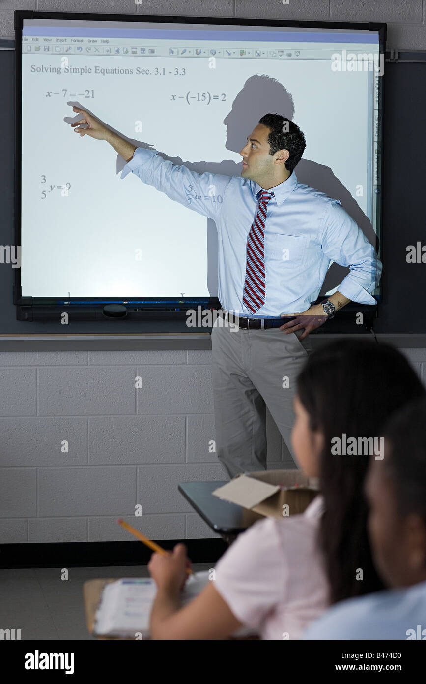 Un insegnante che puntano a somme su uno schermo di proiezione Foto Stock