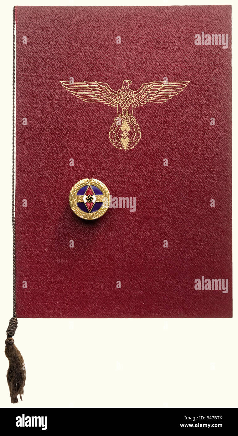 Un distintivo del campionato della gioventù di Hitler, campione della gioventù 1942 in oro Dorato con smalto blu, applied il distintivo della gioventù di Hitler, perno trasversale, nessun marchio del costruttore. Incluso È Un Distintivo Del Campionato Del Distretto Giovanile Di Hitler, 1942. Zinco fine, corona dorata con anno stampato con un distintivo della gioventù di Hitler smaltato applicato separatamente, pin trasversale, produttore Poelath/Schrobenhausen. Inoltre, un documento premio Per 1st Posto nel Royal e Imperial Qualification Shooting Match, 1941, per il distretto Tirol-Vorarlberg. Calligrafia a doppio foglio in una cartella di pelle a imitazione rossa con GO, Foto Stock