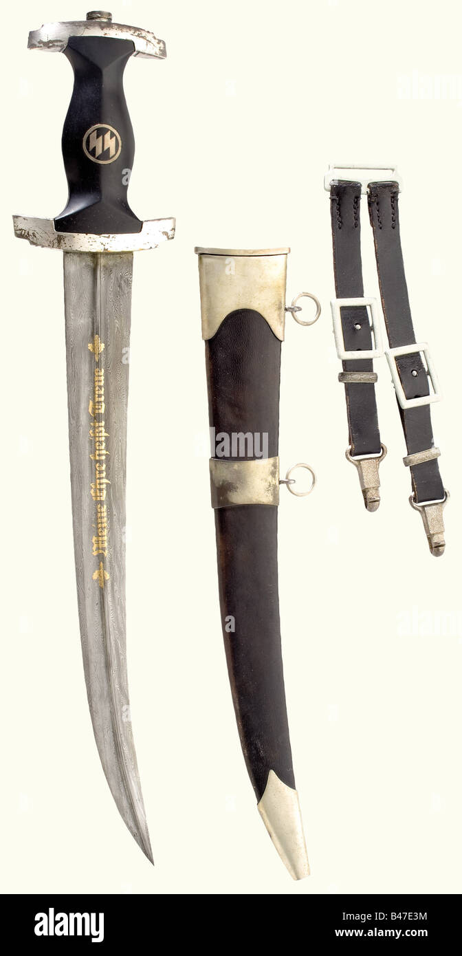 Un pugnale SS a forma di khanjar., pala curva con una nervatura centrale, l'incisione dorata del motto e 'Echt Damast P. Müller' (vera Damasco ...). Quillons argentati. Impugnatura in legno nero con emblema intarsiato. Scabbard rivestito in pelle nera con supporti argentati. Appendiabiti in pelle. Lunghezza 50 cm. La rottura di una collezione di armi orrideI pezzi offerti in questa sezione dell'asta sono stati acquisiti dagli anni post-bellici dal possesso privato o direttamente dai produttori di Solingen, che all'epoca fornivano entrambi alcuni pezzi fantasiosi da r, Foto Stock