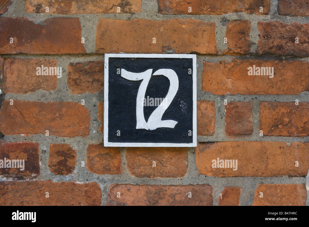 Il numero civico 72 contro in rosso di un muro di mattoni Foto stock - Alamy