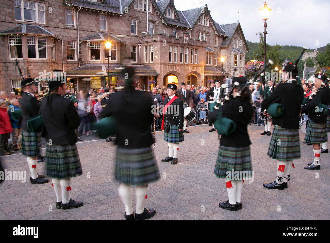 Villaggio di Braemar, Scozia. Il Ballatar Pipe Band giocando in Braemar village, con la Fife Arms Hotel in background. Foto Stock