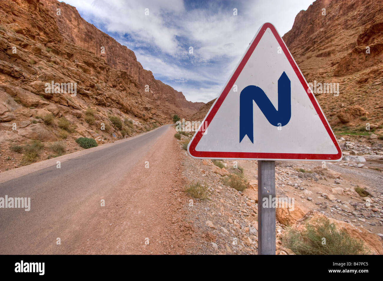 Doppia piega un segnale di avviso nella montagna strada nel deserto Foto Stock