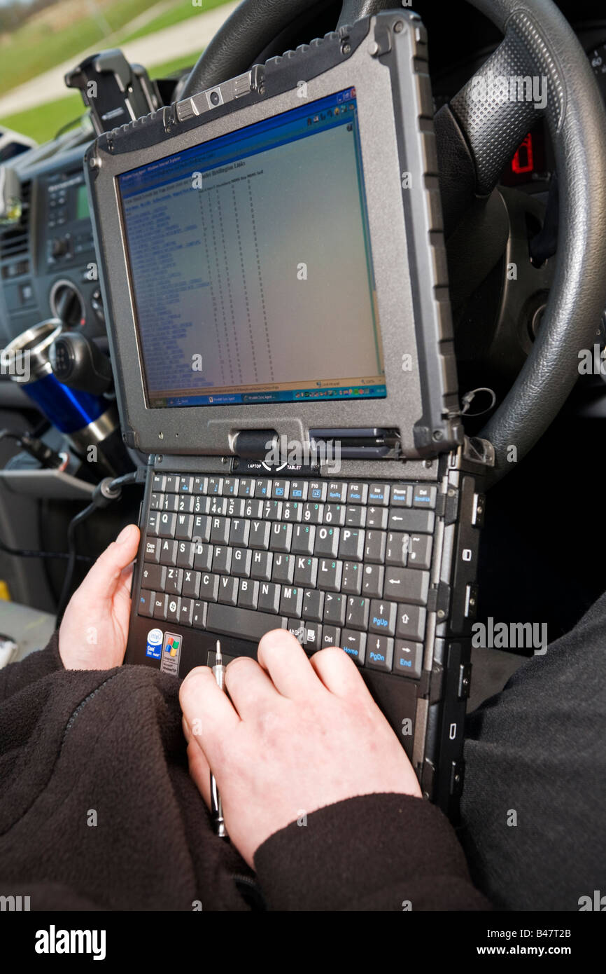 Ingegnere Mobile utilizzando piccole robusto computer portatile nel suo furgone cabina per controllare il suo itinerario con il suo ufficio per restare in contatto Foto Stock