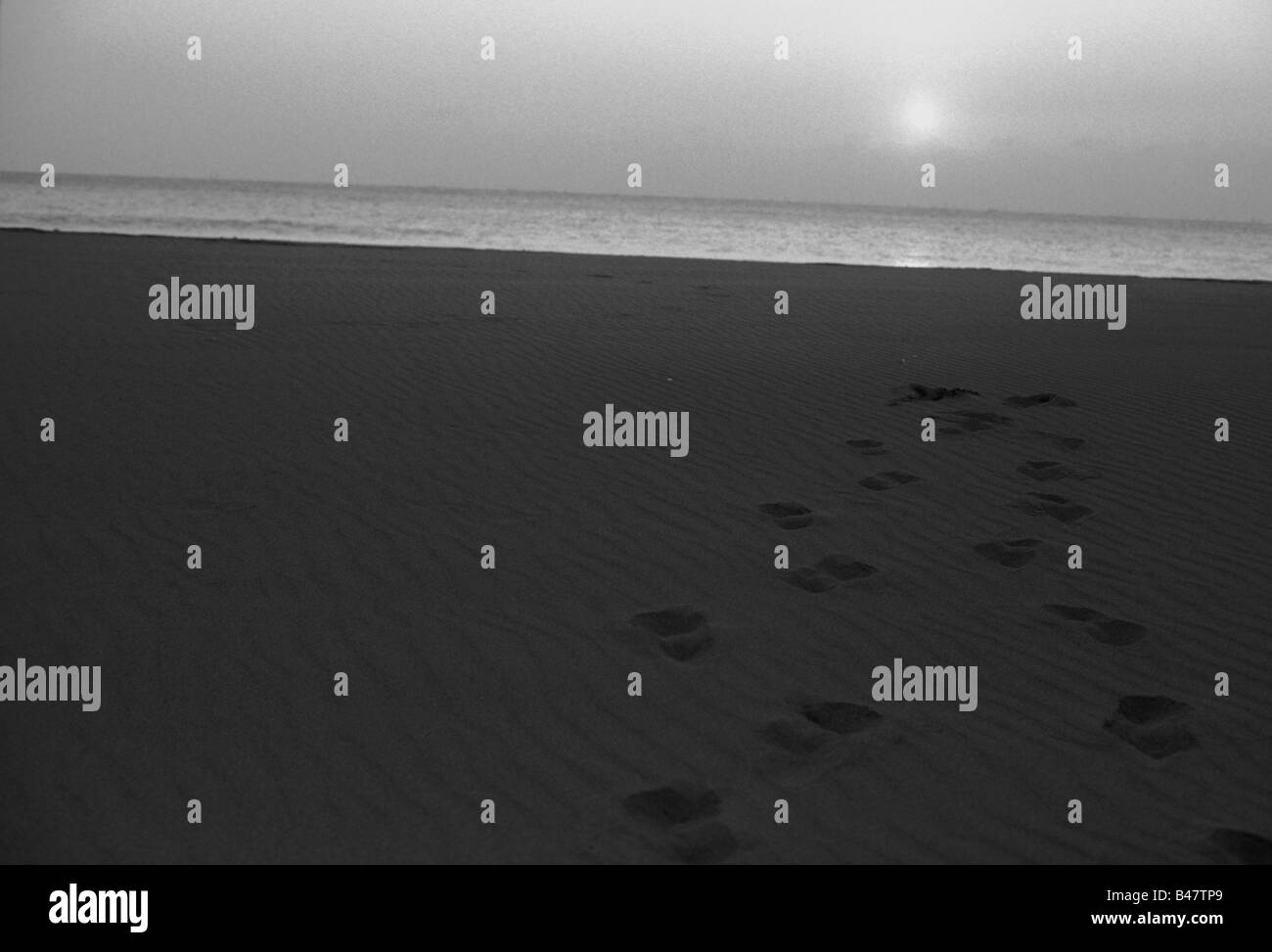 Il backtracking impronte sulla spiaggia al tramonto. Foto Stock