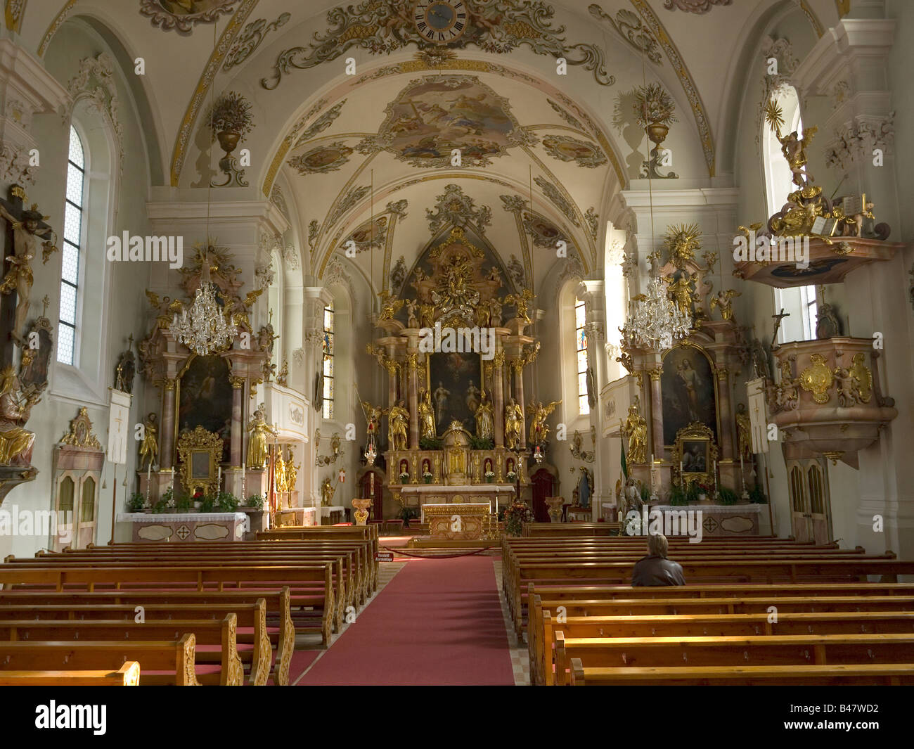 Una donna si siede da solo nella chiesa barocca di Santa Margherita a Oberau Austria Foto Stock