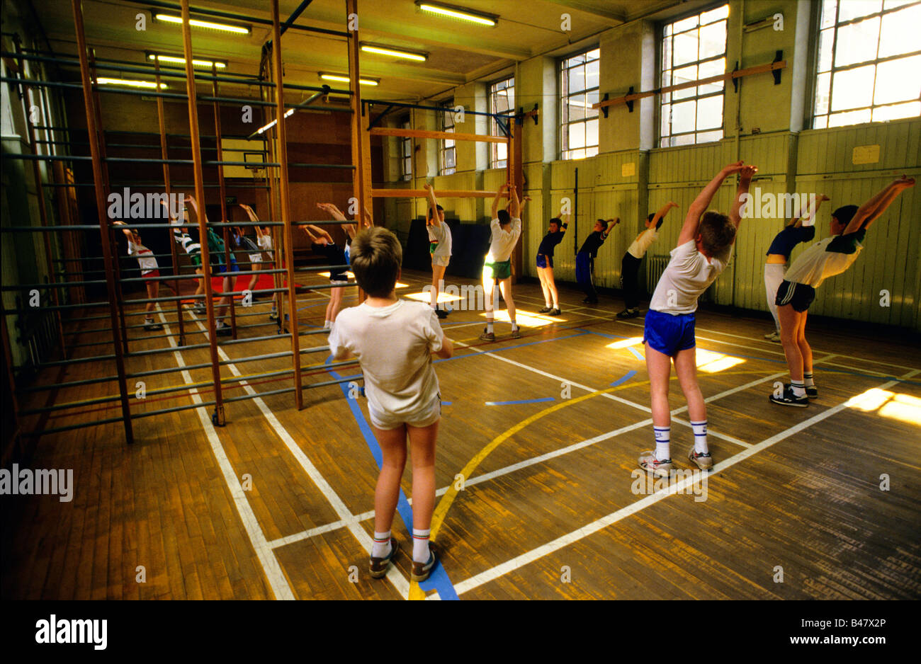 Una classe di ragazzi vanno attraverso streaching esercizi in palestra di una scuola secondaria Foto Stock