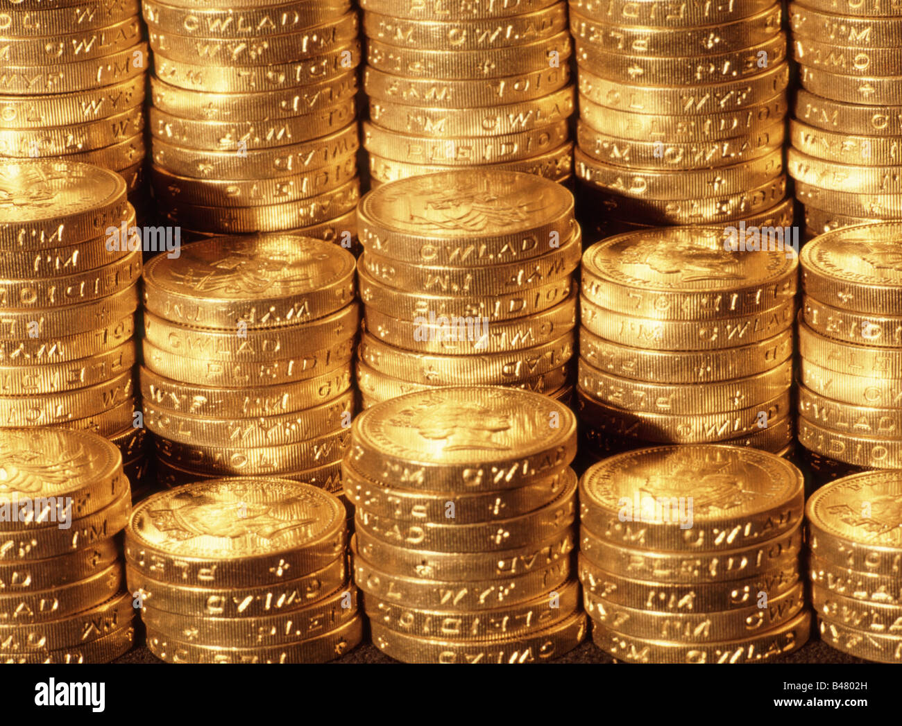 Close up di pile di denaro del Regno Unito una sterlina monete in contanti sotto illuminazione oro Concetto di immagine per nido uovo pila di risparmio di denaro di pile di denaro Foto Stock