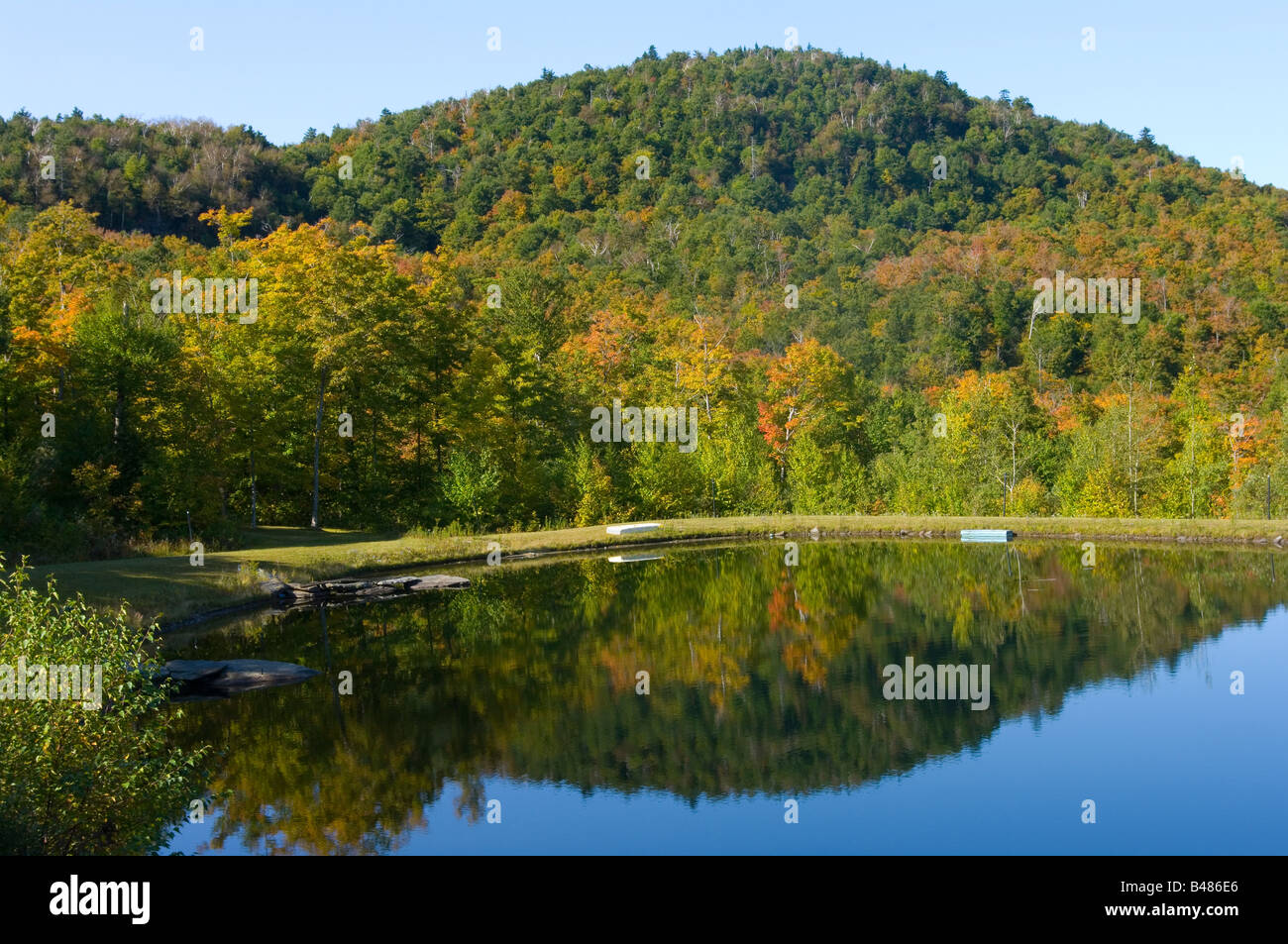 Ancora stagno ai piedi di una collina del Vermont boscoso in autunno i colori miscelati con verde Foto Stock
