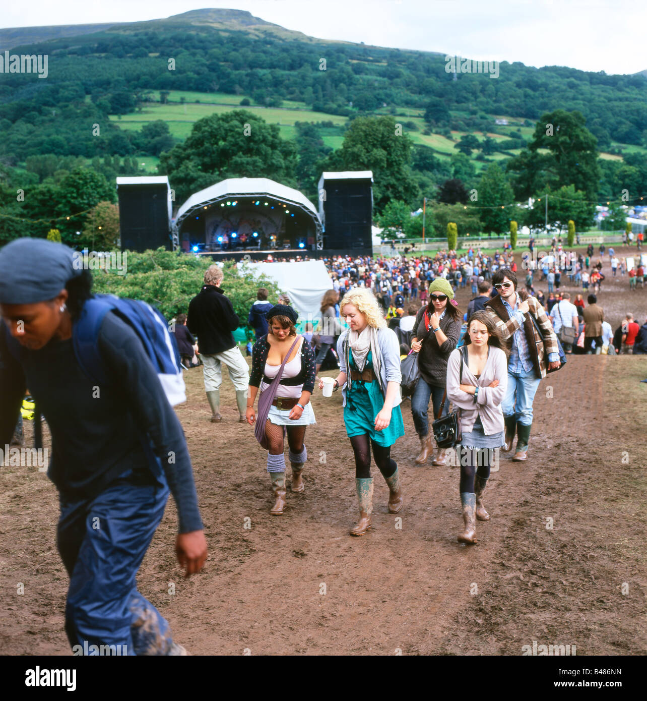 I frequentatori del festival scalare una collina fangosa al Green Man Festival presso Glanusk vicino a Abergavenny in Galles Centrale REGNO UNITO Foto Stock