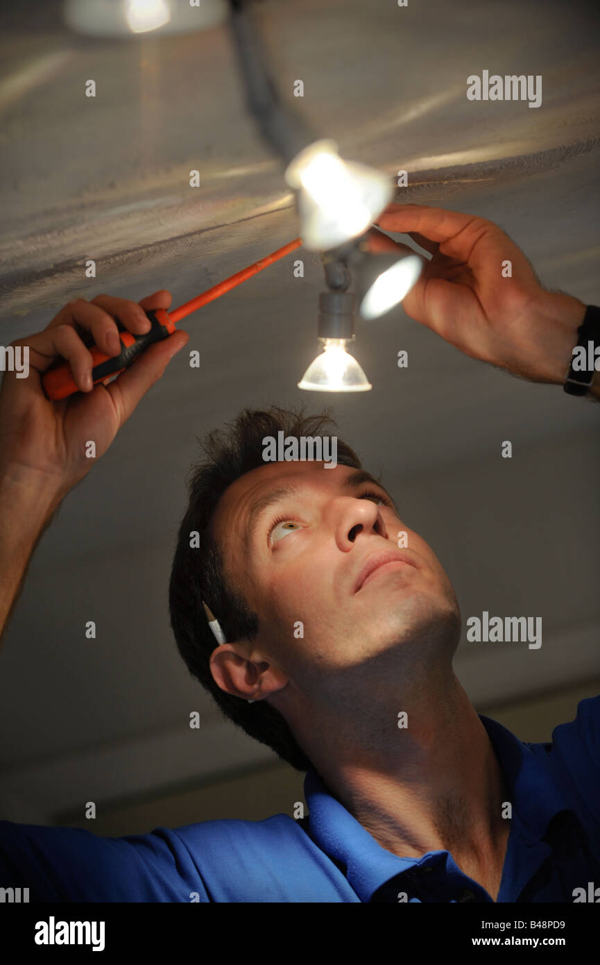 Un elettricista lavorando su 12 volt luce tracking. Foto da Jim Holden. Foto Stock