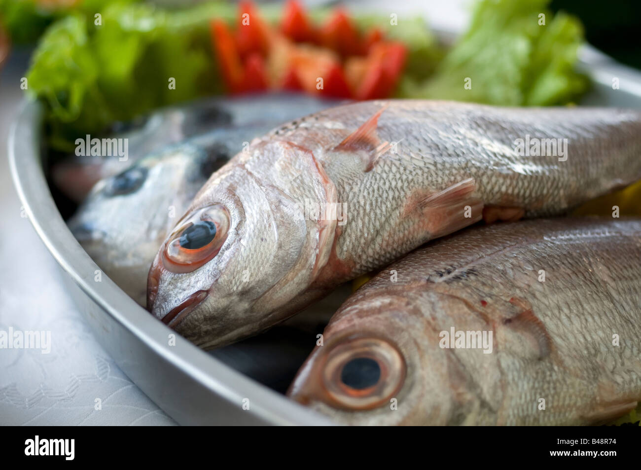 Alcuni cardinalfishes sopra un vassoio con verdure Foto Stock