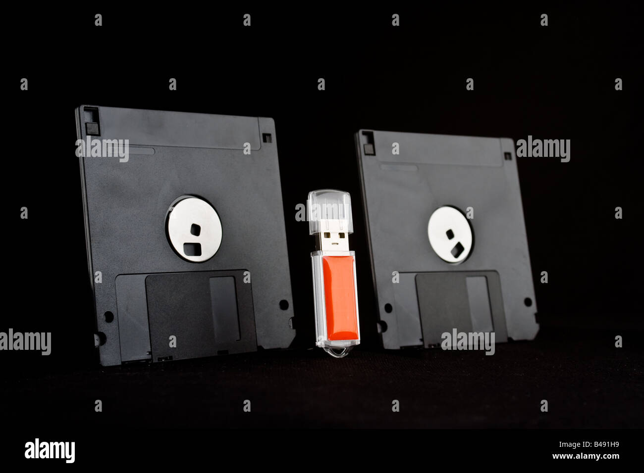Due dischetti floppy su entrambi i lati di un rosso chiave di memoria usb, dando l'aspetto di vecchia tecnologia minacciando la nuova tecnologia. Foto Stock