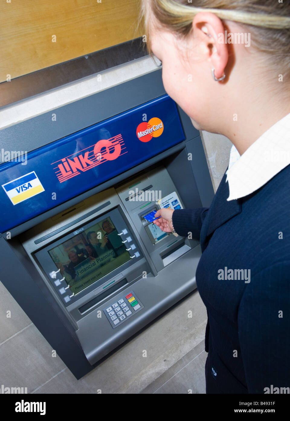 Giovane imprenditrice in completo inserimento di scheda in un collegamento punto di contanti macchina ATM REGNO UNITO Foto Stock