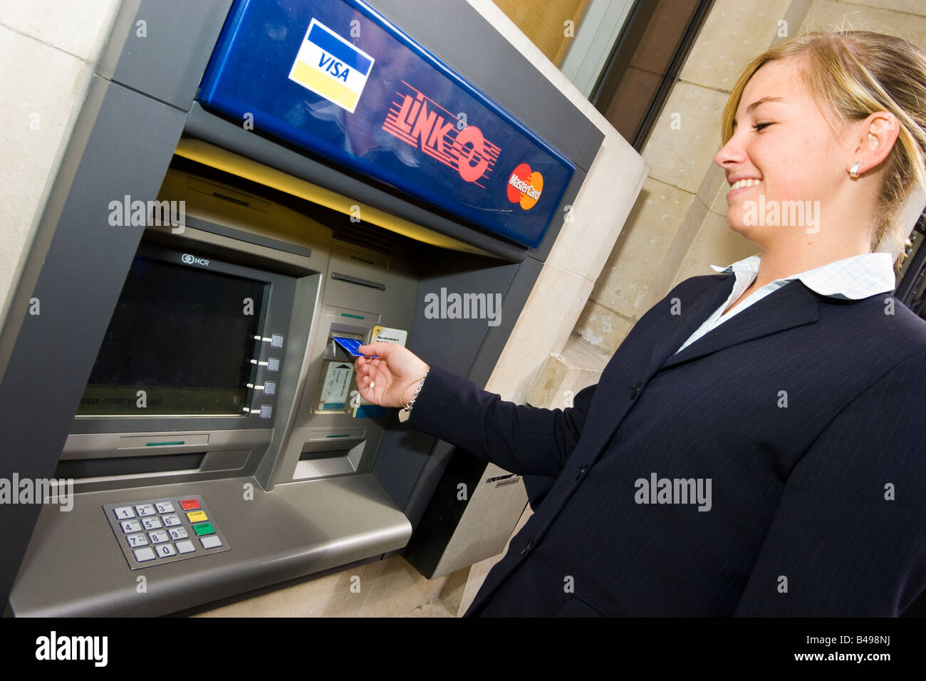 Donna che utilizza un collegamento bancomat ATM cash point REGNO UNITO Foto Stock