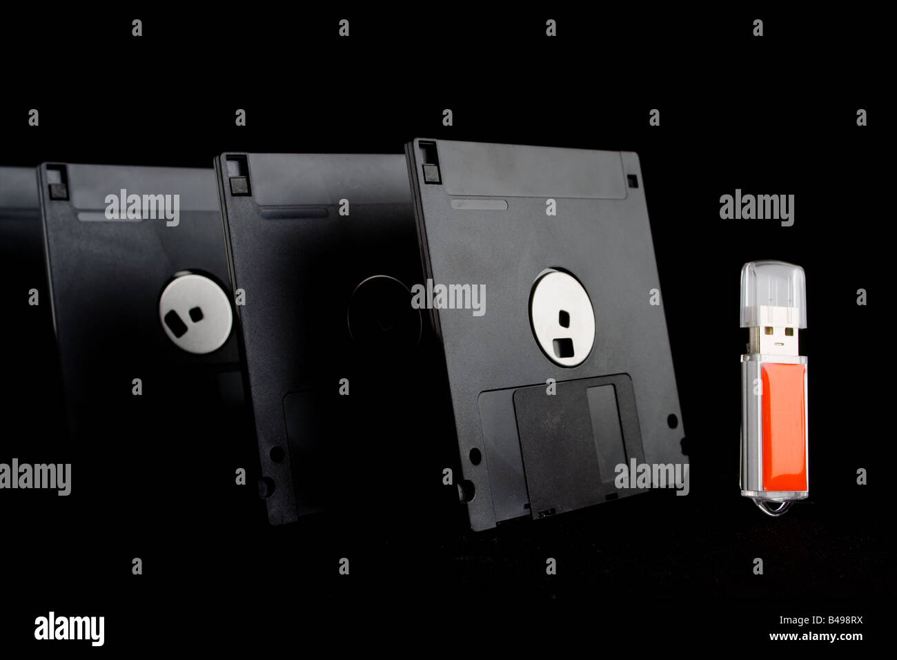 Quattro dischetti floppy allineate su un lato di un rosso chiave di memoria usb, dando l'aspetto di vecchia tecnologia minacciando la New Tech Foto Stock