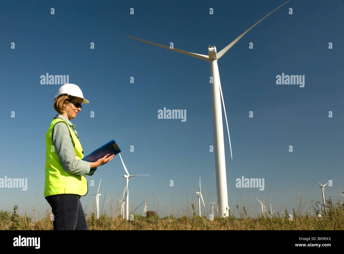 Ingegnere femmina collare verde posti di lavoro accanto alla turbina eolica wind farm Foto Stock