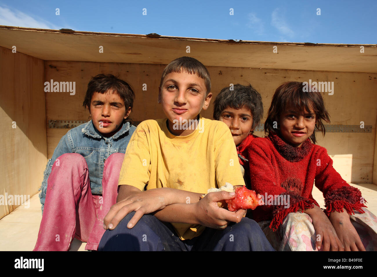 Roma bambini zingari seduti in una scatola a condividere, una delle baraccopoli accanto a una discarica alla periferia di Tirana, Albania Foto Stock