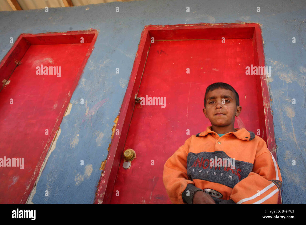 Roma gypsy boy in piedi di fronte a servizi igienici accanto alla sua casa in Korca, Albania Foto Stock