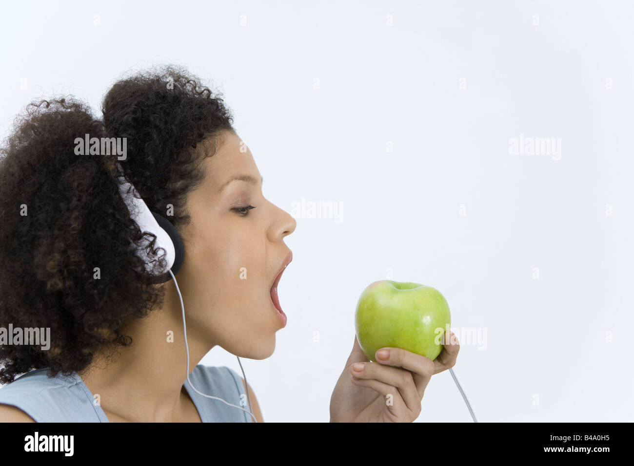 Donna ascoltando le cuffie collegate a Apple, a bocca aperta, profilo Foto  stock - Alamy