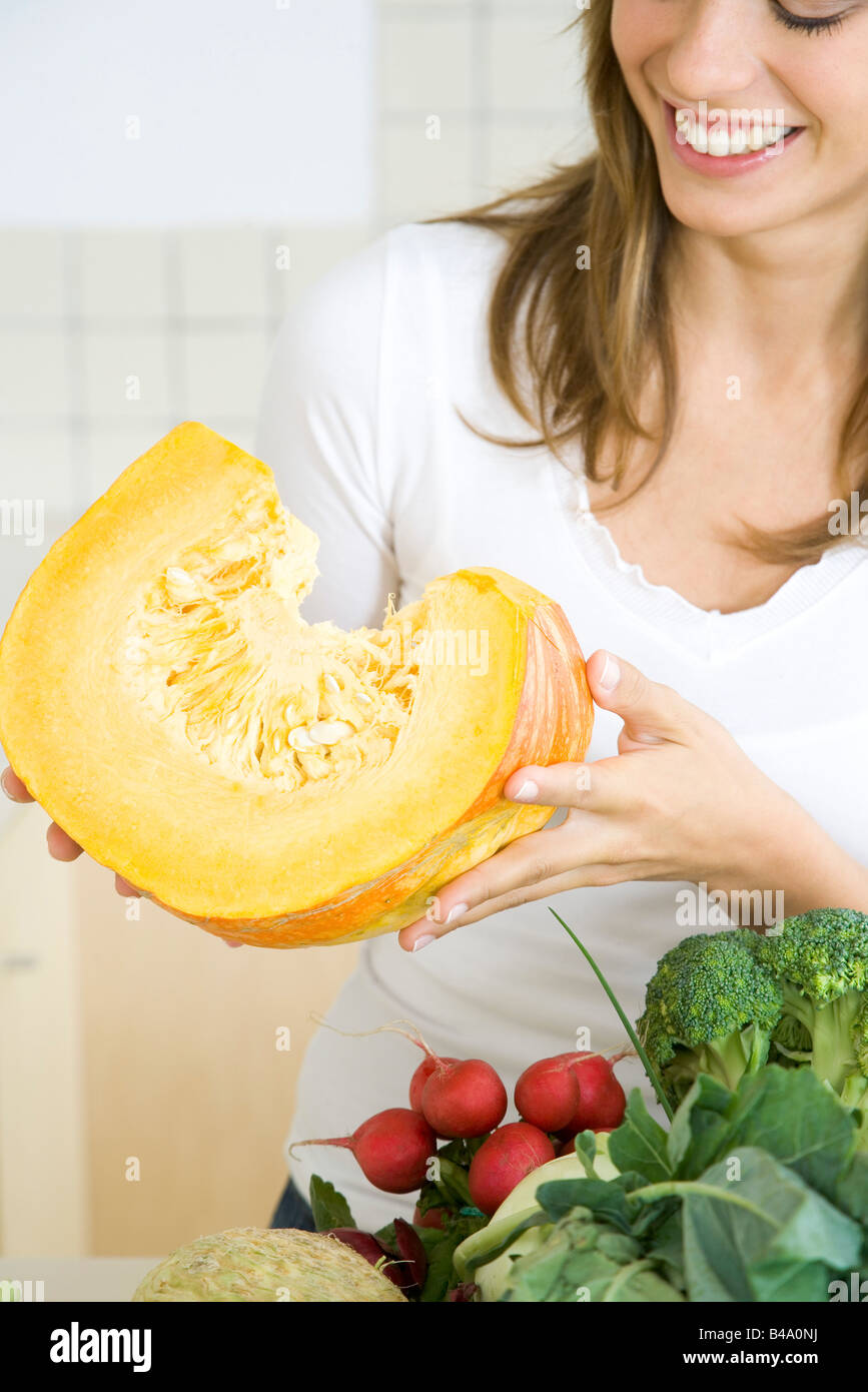 Donna che mantiene grande fetta di zucca raw, sorridente Foto Stock