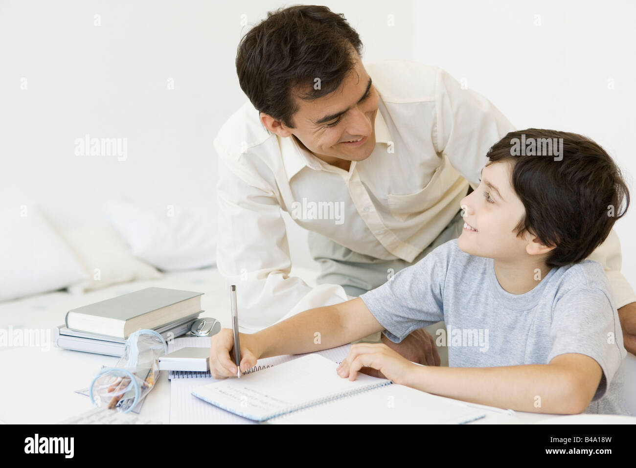 Padre aiutando figlio con compiti sia di sorridere a ogni altro Foto Stock