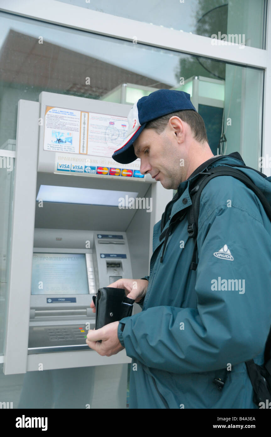 Uomo con portafogli vicino a ATM Foto Stock