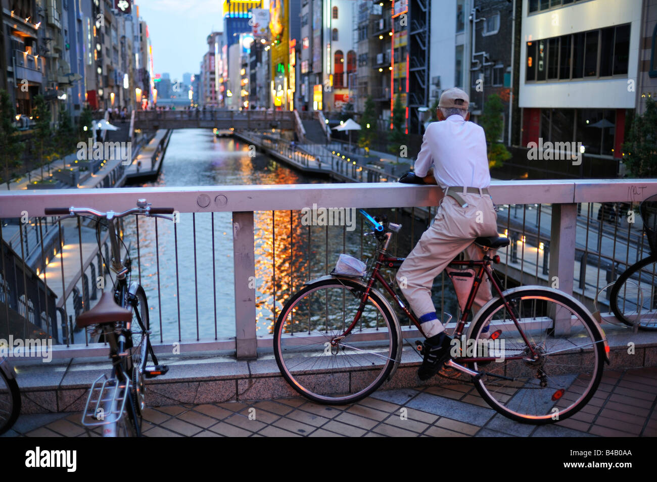 Un anziano giapponese che guarda il crepuscolo nell'affollato canale Dotonbori, Osaka JP Foto Stock