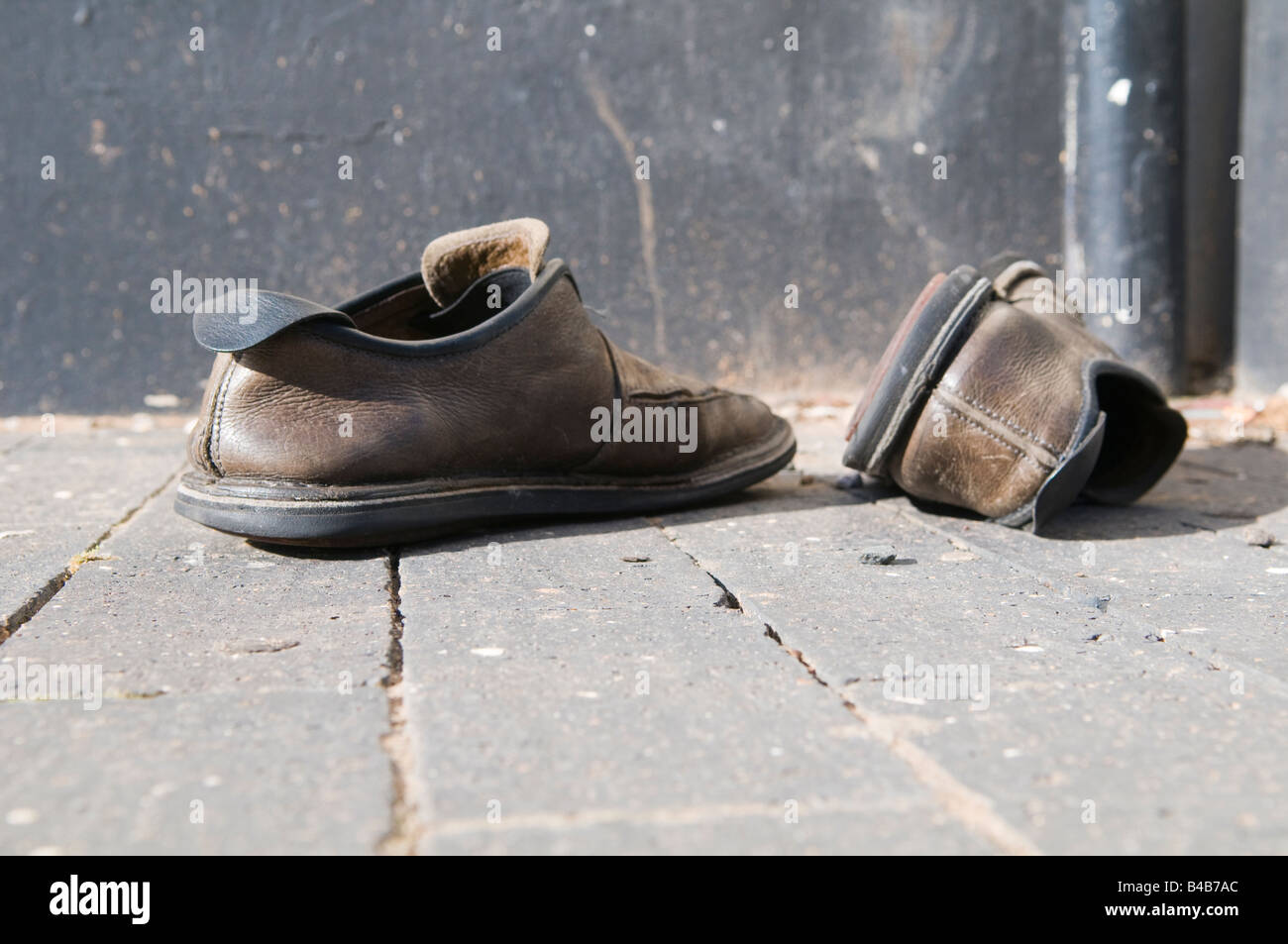 Coppia di vecchie scarpe a sinistra su un marciapiede Foto Stock