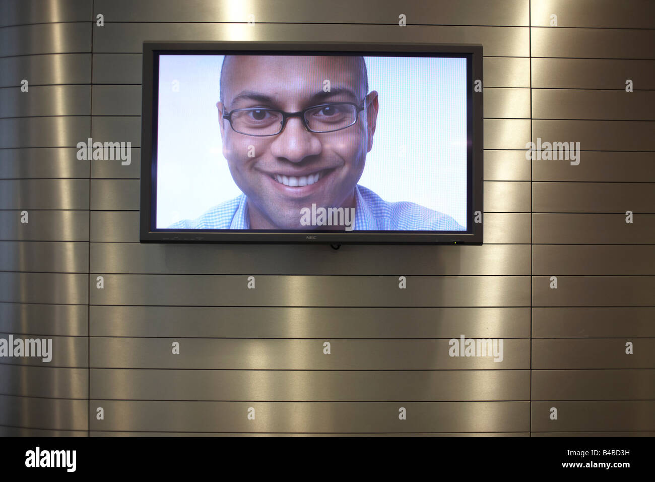 Schermo TV visualizzando il messaggio di saluto aziendale Smiley face all'ingresso principale di una società di auditing la sede centrale europea Foto Stock