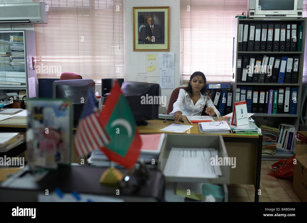 Il dipendente di sesso femminile di Cyprea alimenti marini funziona sotto il ritratto di Maldive ex-Presidente Gayoom nella capitale Malé Foto Stock