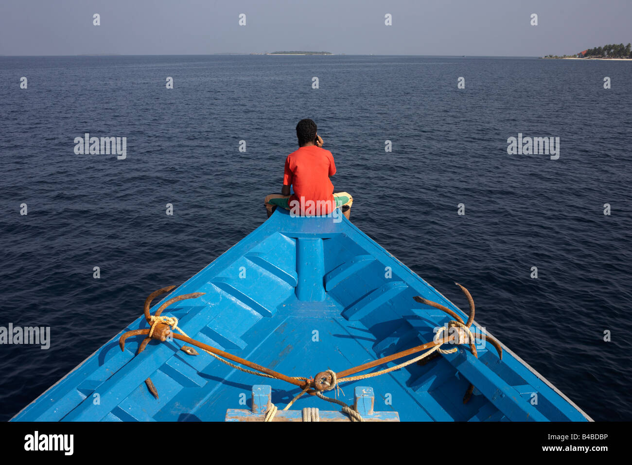 Un crewman maldiviano utilizza un telefono cellulare dopo una giornata di pesca al tonno a bordo di un dhoni barca da pesca in una zona remota dell Oceano Indiano Foto Stock
