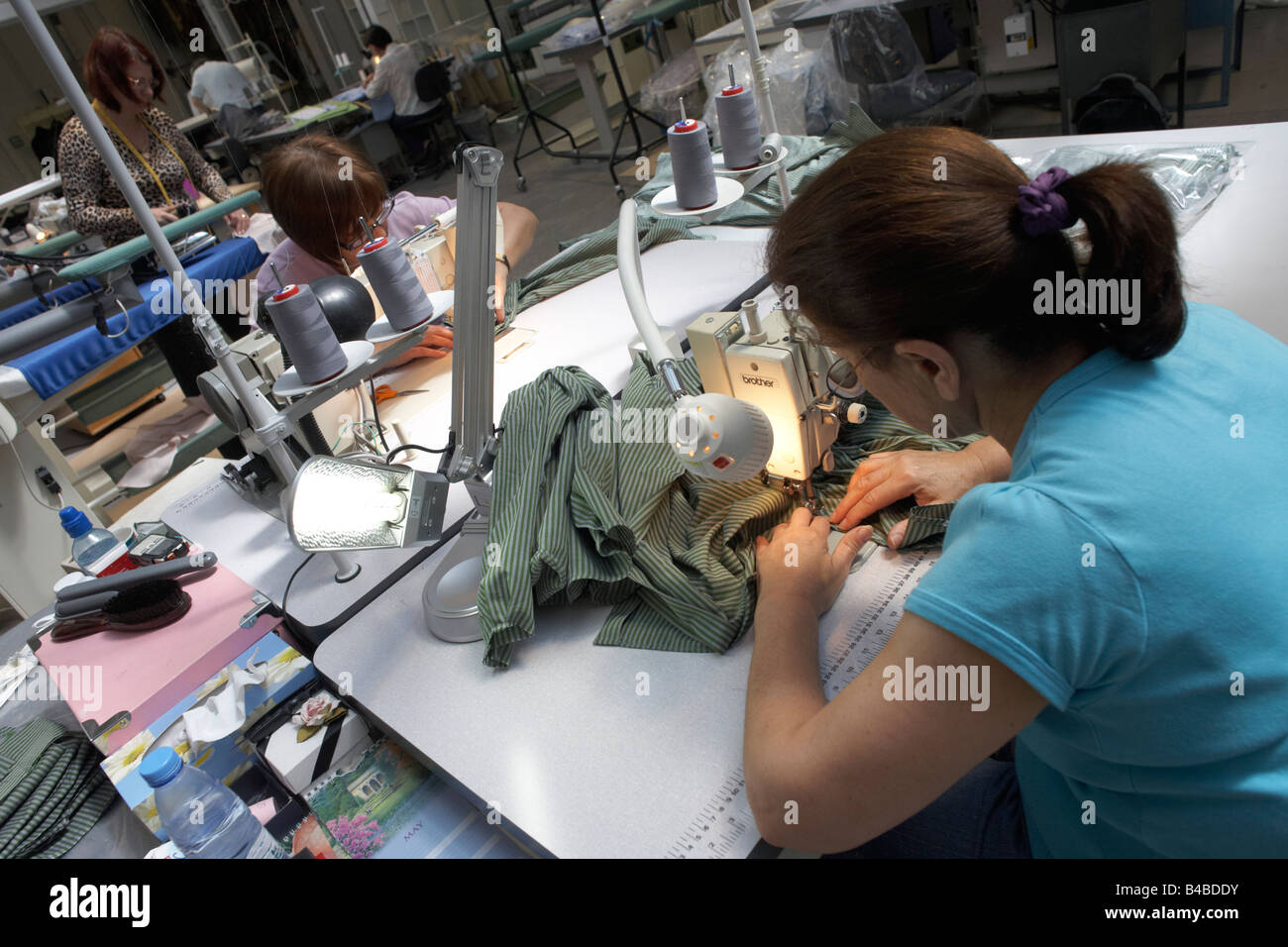 Team di seamstresses corri su capi su macchine da cucire a couturier Margaret Howell di Edmonton factory workshop Foto Stock