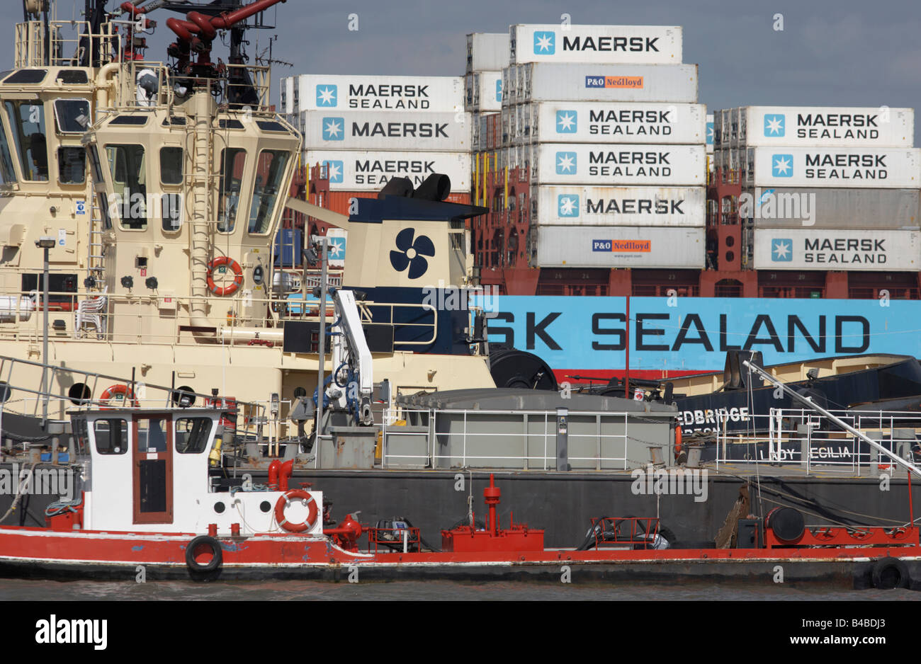 Un assortimento di navigazione sul fiume Tamigi: la nave portacontainer in background, due rimorchiatori, un galleggiante grigio pier e il rifornitore Foto Stock