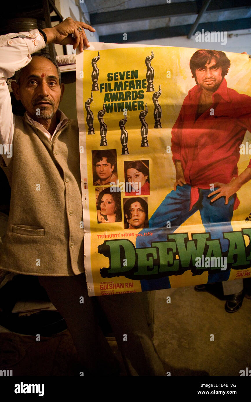 Un uomo tiene fuori un poster pubblicitari un Amitabh Bachchan film in un film ai distributori di Varanasi (India). Foto Stock